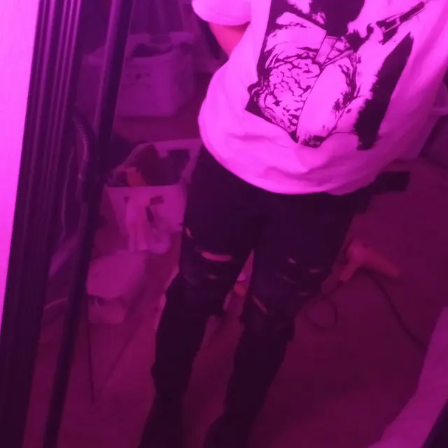 Person wearing a hoodie with a graphic design in a dimly lit room with purple lighting.